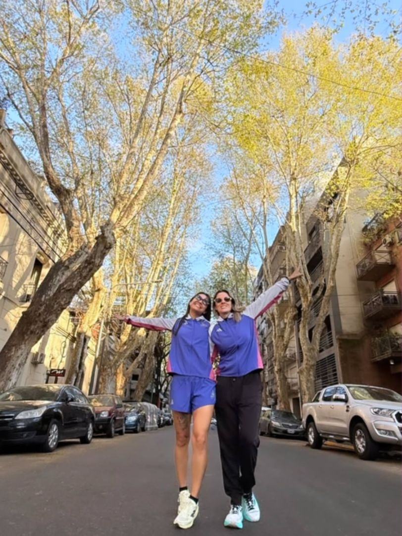 Duas atletas celebrando em rua arborizada